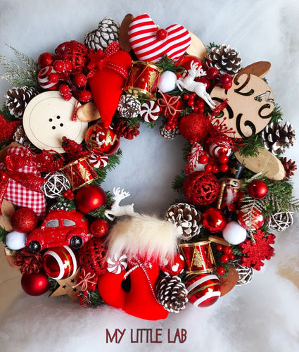 Στεφάνι Χριστουγεννιάτικο  σε κόκκινες αποχρώσεις σε βάση πράσινη με κλαδιά , στολισμένο με στοιχεία υφασμάτινα , ξύλινα  και πολλά διαφορετικά στολίδια  όλων των τύπων. 